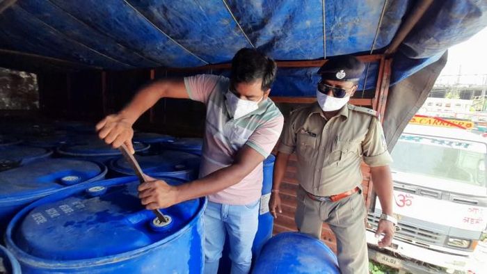 কাঁচা স্পিরিটের ট্রাক থেকে ঢাকনা খুলছেন পুলিশ কর্মীরা