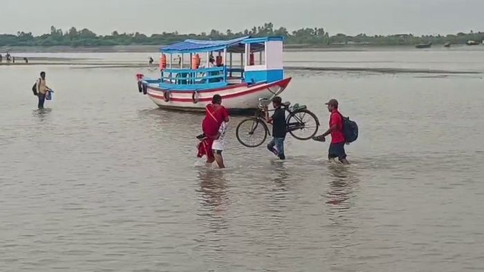 স্ত্রীকে কোলে নিয়ে নদী পেরোচ্ছেন ব্যক্তি