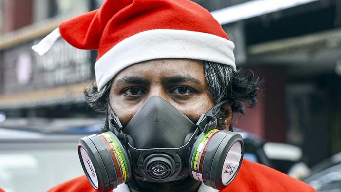 দিল্লিতে বায়ুদূষণের জেরে জেরবার এক যুবক সান্তা ক্লজের পোশাকেও দূষণ ঠেকাতে মাস্ক পরেছেন (ছবি PTI)