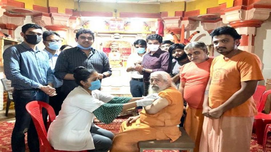 मंदिर में महंत को टीका लगाती स्वास्थ्यकर्मी. मंदिर में महंत को टीका लगाती स्वास्थ्यकर्मी.