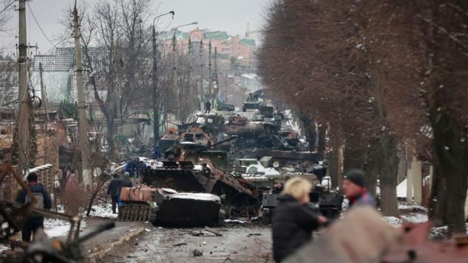 People look at the gutted remains of Russian military vehicles on a road in the town of Bucha People look at the gutted remains of Russian military vehicles on a road in the town of Bucha