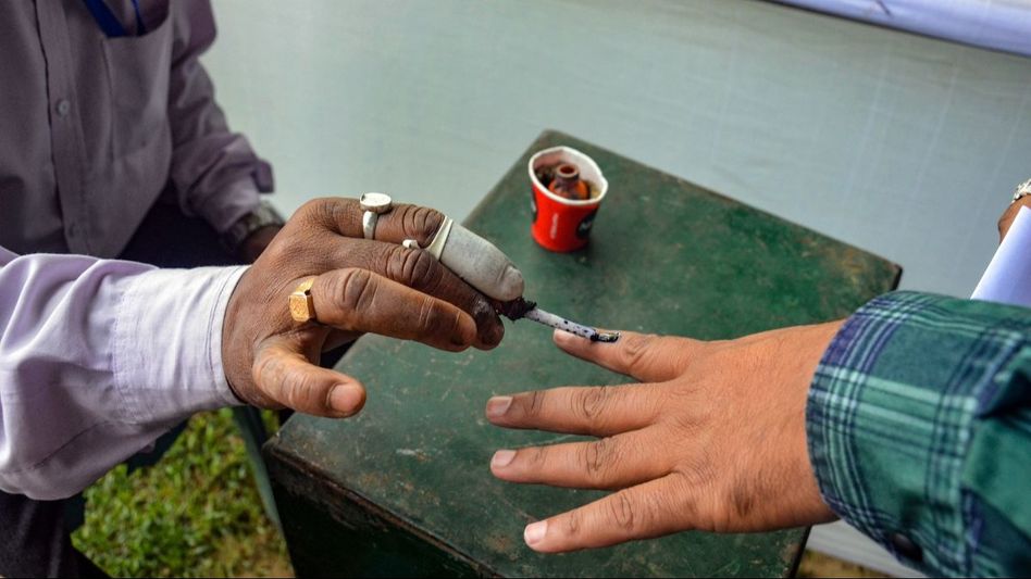 An election official marks the finger of a polling official with indelible ink An election official marks the finger of a polling official with indelible ink