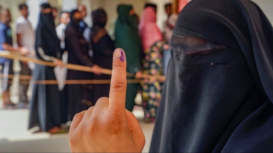 A burqa clad woman shows her ink-marked finger after casting her vote A burqa clad woman shows her ink-marked finger after casting her vote