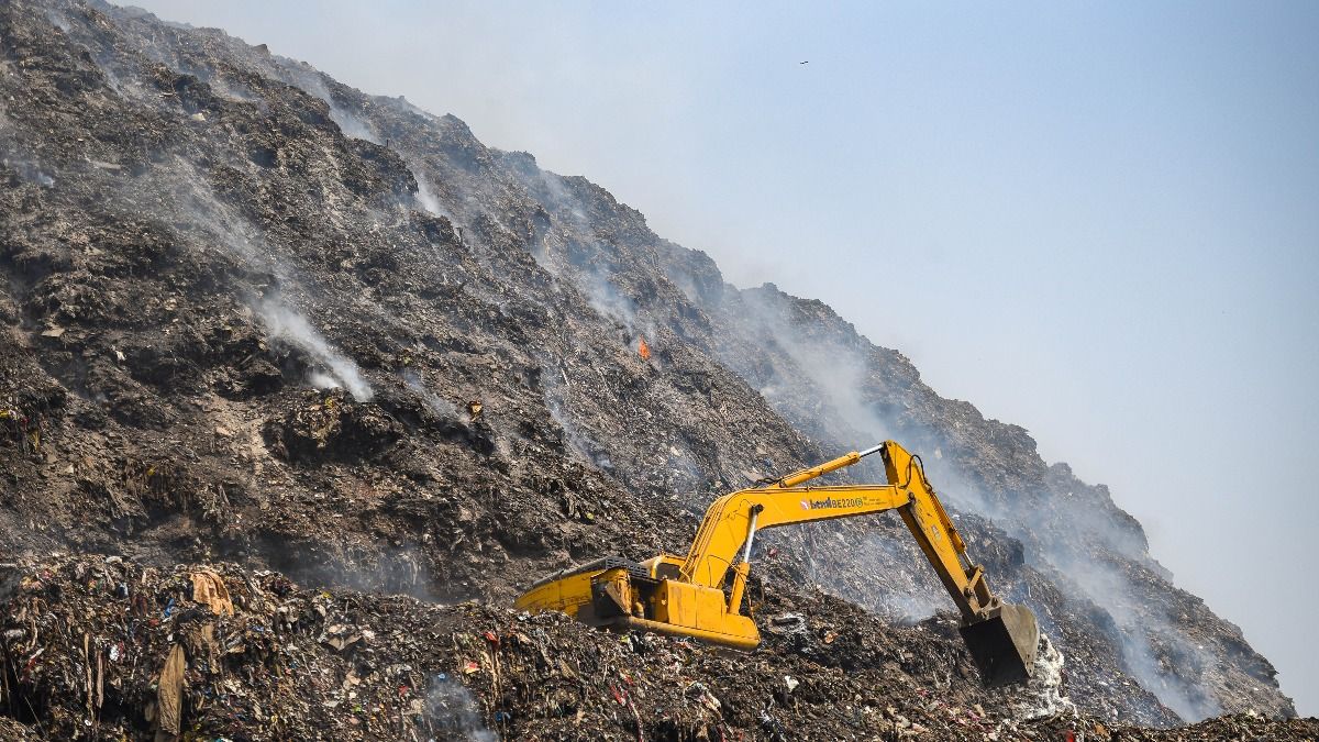 An excavator at work as smoke continues to rise from the Bhalswa landfill site where a fire broke out on April 26, on May 1, 2022 in New Delhi, India. An excavator at work as smoke continues to rise from the Bhalswa landfill site where a fire broke out on April 26, on May 1, 2022 in New Delhi, India.
