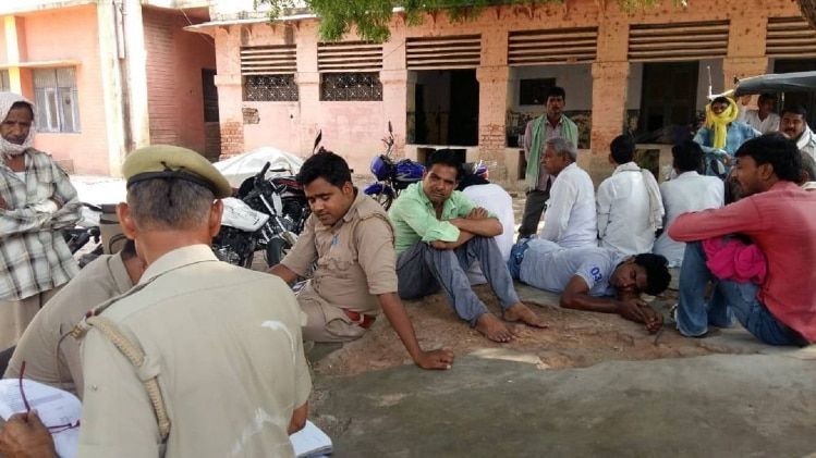 मृतक किसान के घर के बाहर जमा लोग और पुलिस