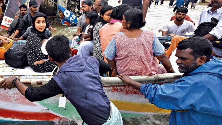 बचाव पंडालम में फंसे लोगों को बाहर निकालते मछुआरे और दूसरे लोग