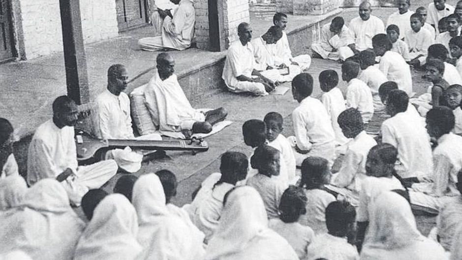 विनम्रता के साथ 1930 में सहयोगियों और छात्र-छात्राओं को संबोधित करते गांधी (बाएं से चौथे)