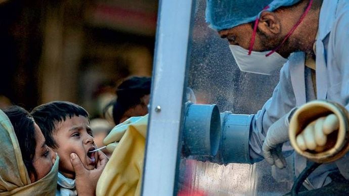दिल्ली के एक इलाके में नमूने एकत्र करता चलता-फिरता कोविड-19 जांच वैन (फोटोः पंकज नागिया)