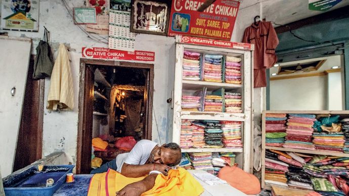 कहां का धंधा? लखनऊ में चौक स्थित चिकन प्रिंटिंग और एम्ब्रॉइडरी शॉप में ग्राहक न होने से आराम करता दुकानदार