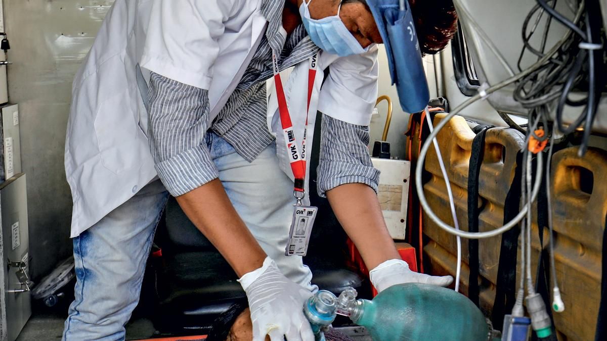 अहमदाबाद के एक अस्पताल के बाहर एंबुलेंस में मरीज का ऑक्सीजन मास्क ठीक करता स्वास्थ्यकर्मी