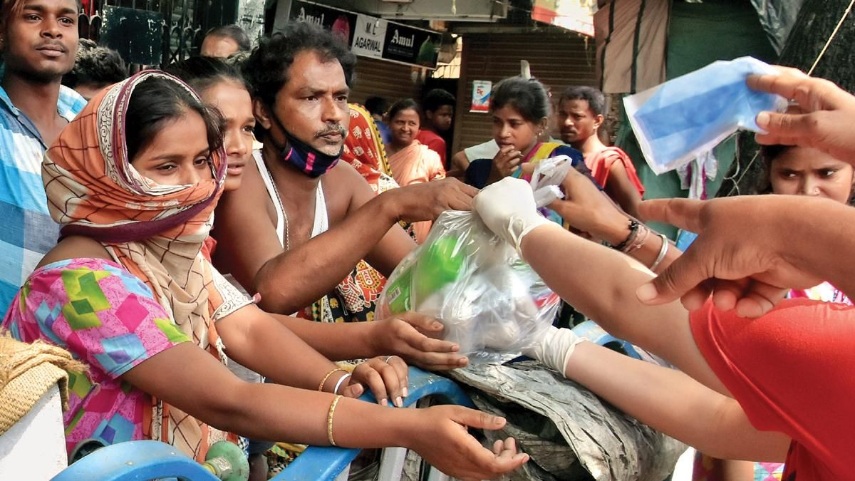 मजबूरी कोलकाता में गरीबों को खाद्य पैकेट बांटते एनजीओ कार्यकर्ता