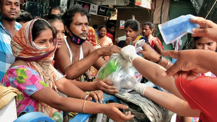 मजबूरी कोलकाता में गरीबों को खाद्य पैकेट बांटते एनजीओ कार्यकर्ता