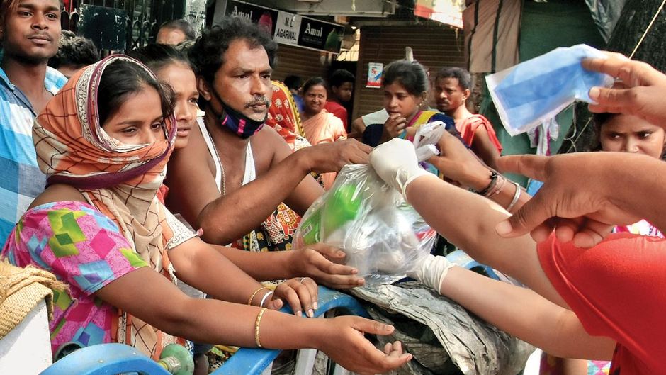 मजबूरी कोलकाता में गरीबों को खाद्य पैकेट बांटते एनजीओ कार्यकर्ता
