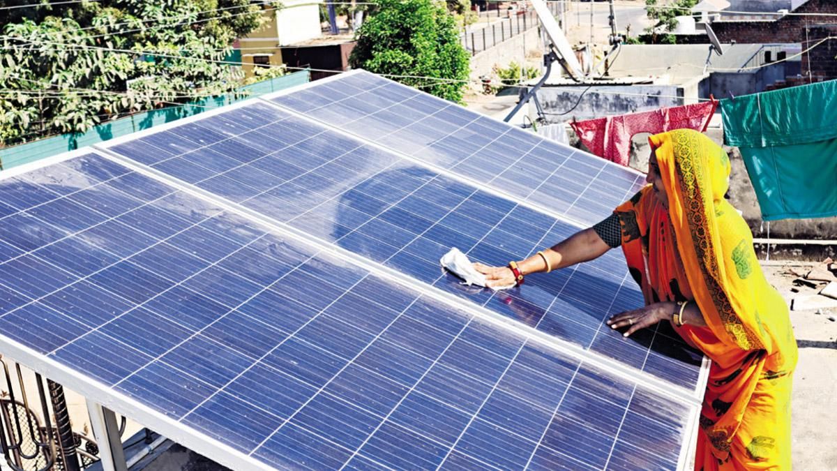 सुनहरा समय : मोढेरा के एक गांव में छत पर सोलर पैनल साफ करती एक महिला