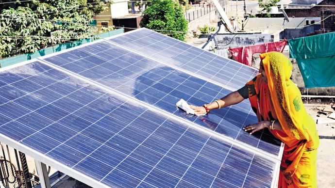 सुनहरा समय : मोढेरा के एक गांव में छत पर सोलर पैनल साफ करती एक महिला