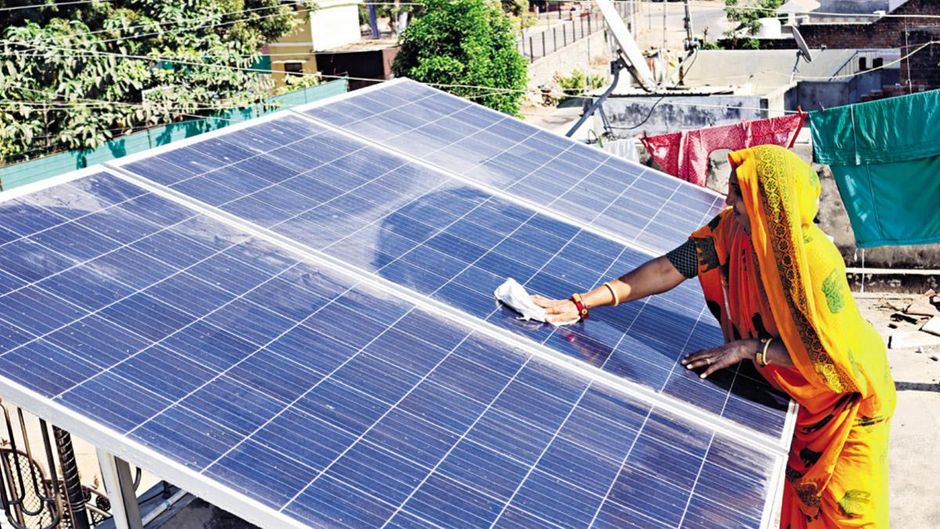 सुनहरा समय : मोढेरा के एक गांव में छत पर सोलर पैनल साफ करती एक महिला