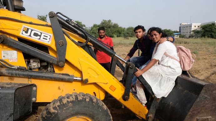 बुलडोजर रोकने के लिए इसके ऊपर चढ़े युवा