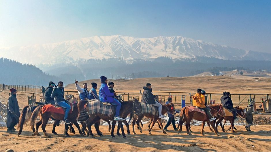 गुलमर्ग की बर्फरहित ढलानों पर घुड़सवारी का आनंद लेते पर्यटक