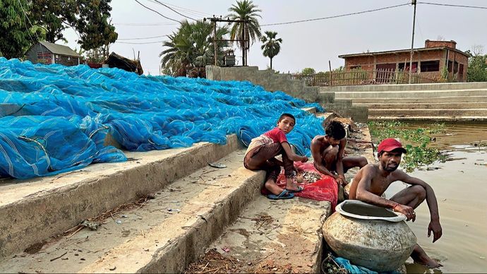 दरभंगा के बिरौल के पास एक गांव में तालाब किनारे सूख रहा जाल और मछली पकड़ते निषाद जाति के लोग
