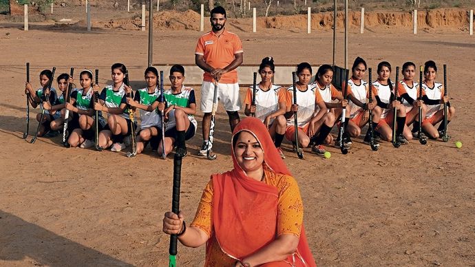 गांव के मैदान में हॉकी खिलाड़ियों के साथ सरपंच नीरू यादव