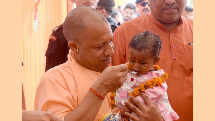 गोरखपुर के वनटांगिया गांव में बच्चे का अन्नप्राशन करते मुख्यमंत्री योगी आदित्यनाथ
