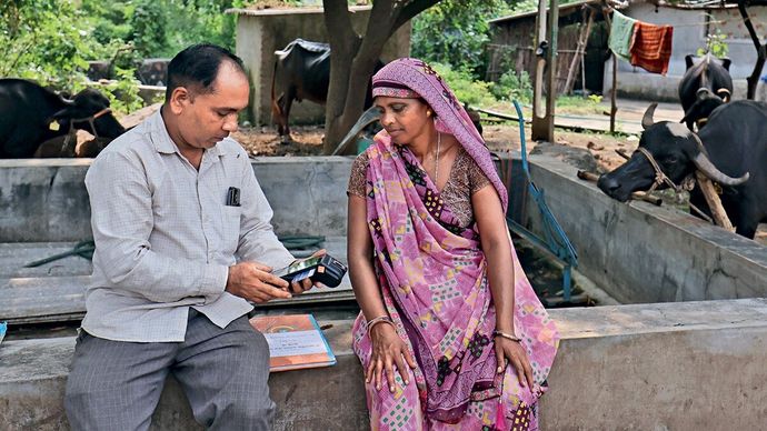 बैंक मित्र कल्पेश पटेल की मदद से माइक्रो एटीएम का इस्तेमाल कर रहीं डेयरी किसान कोकिलाबेन पटेल
