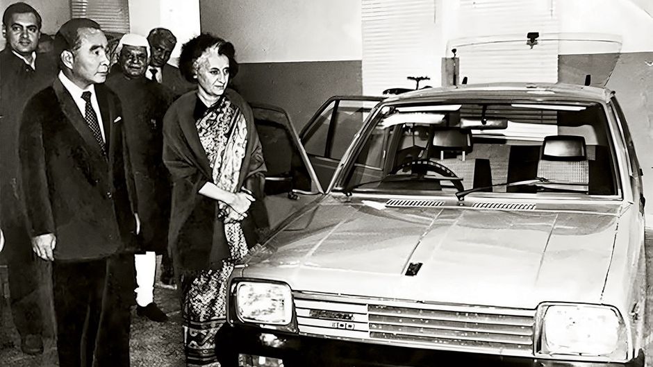 प्रधानमंत्री इंदिरा गांधी, राजीव गांधी (सबसे बाएं) और सुजुकी के चेयरपर्सन ओ. सुजुकी दिसंबर 1983 में नई दिल्ली में मारुति 800 कार के साथ