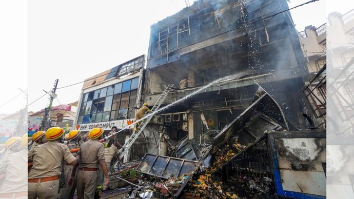 Fire personnel conduct a dousing operation after fire broke out at a commercial building in Aliganj, Lucknow