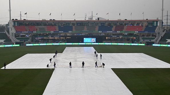 Ground staff cover the pitch as it rains before the start of the ICC Champions Trophy one-day international (ODI) cricket match between Pakistan and Bangladesh at the Rawalpindi Cricket Stadium in Rawalpindi on February 27, 2025.