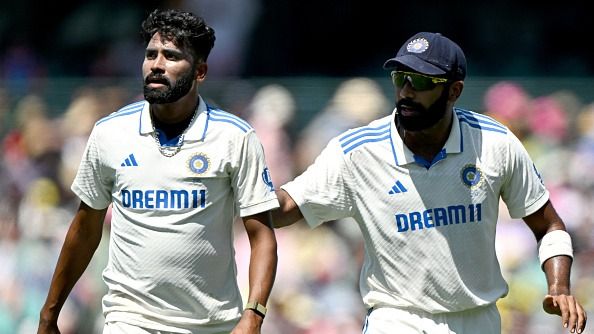 India's captain Jasprit Bumrah (R) gives instructions to Mohammed Siraj as he prepares for his bowling run-up on day two of the fifth Test match between Australia and India