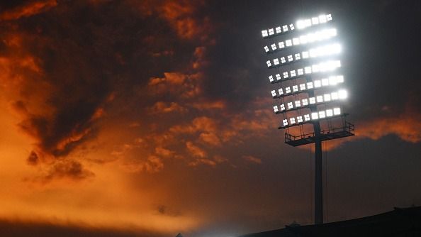 A view of a flood light as the sun sets behind the stadium A view of a flood light as the sun sets behind the stadium
