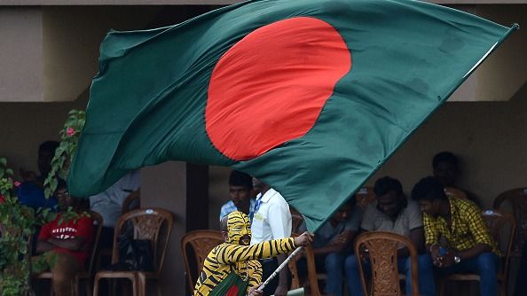 A Bangladeshi cricket supporter, with his face painted in the style of a tiger, waves his national flag during the fourth day of the opening Test match between Sri Lanka and  Bangladesh at the Galle International Cricket Stadium