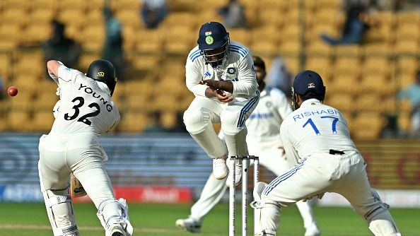 New Zealand's Will Young (L) plays a shot as India's Sarfaraz Khan (C) jumps to field 