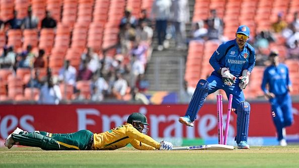 क्विंटन डी कॉक (L) क्रीज तक पहुंचने के लिए स्ट्रेच करते हुए, अफगानिस्तान के विकेटकीपर रहमानुल्लाह गुरबाज उन्हें आउट करने की कोश‍िश करते हुए (PC: Getty)