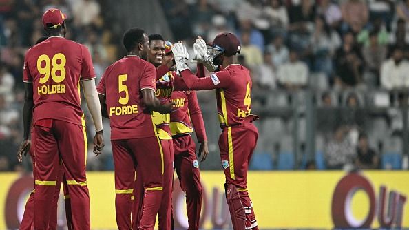 West Indies' Akeal Hosein (C) celebrates with teammates after taking the wicket of Zimbabwe's Brian Bennett