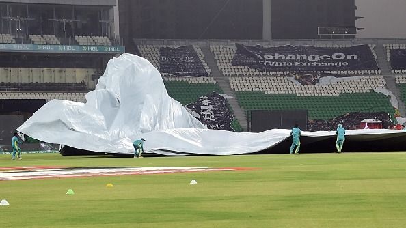 Ground staff cover the pitch before rain