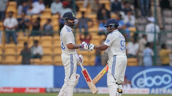 Virat Kohli of India is congratulated by team mate Sarfaraz Khan after scoring a half century during day three of the First Test match between India and New Zealand at M. Chinnaswamy Stadium