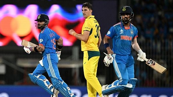 India's Virat Kohli (L) and KL Rahul run between the wickets past Australia's captain Pat Cummins (C) during the 2023 ICC Men's Cricket World Cup
