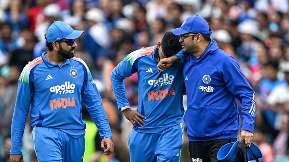 Shreyas Iyer (C) reacts in pain after falling on the ground while taking a catch to dismiss Australia's Alex Carey as his teammate Rohit Sharma (L) watches during the third one-day international (ODI) men's cricket match