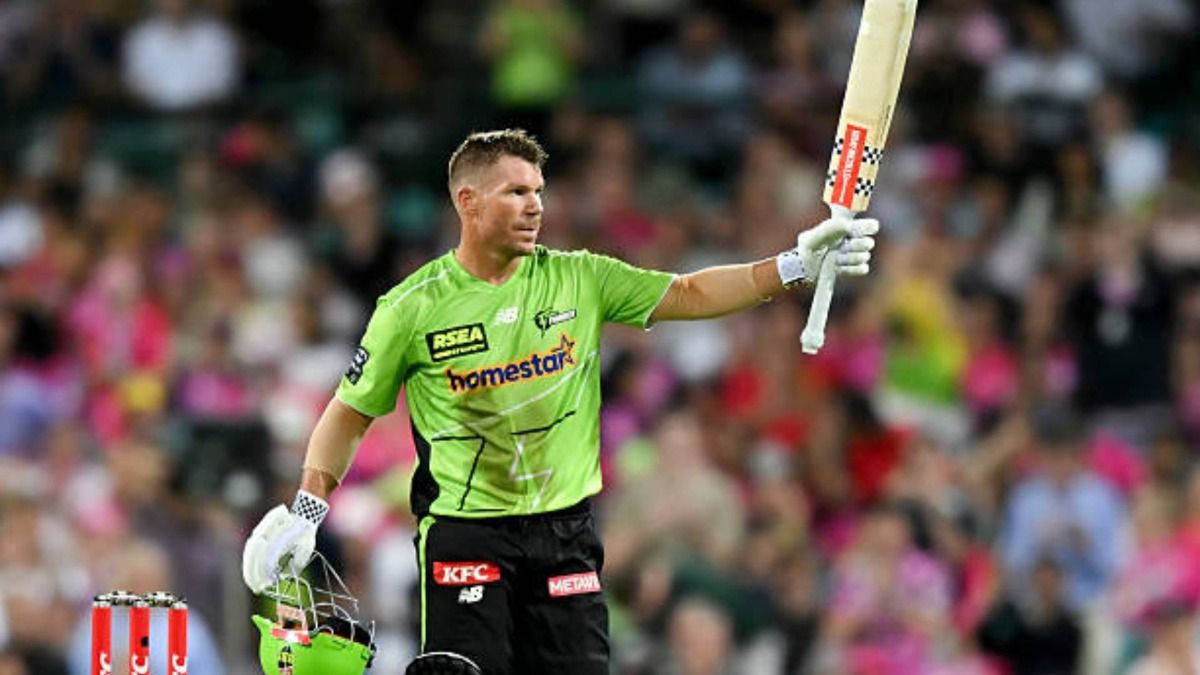 David Warner of Sydney Thunder raises the bat to celebrate after completing a century (100 runs) during the BBL match between Sydney Sixers and Sydney Thunder at the Sydney Cricket Ground (via Getty)