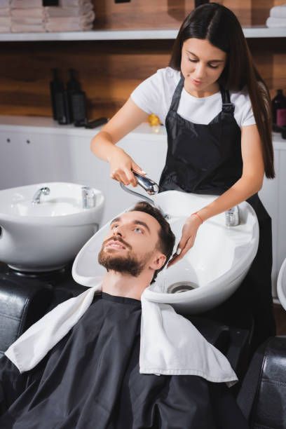 young hairdresser washing hair of client in beauty salon