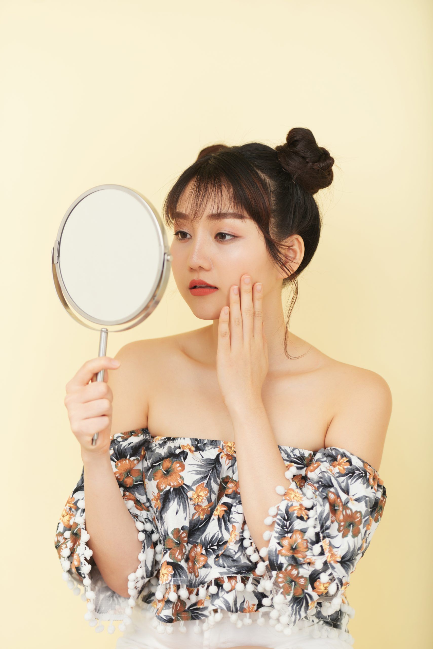 young-asian-woman-with-bare-shoulders-posing-studio-looking-hand-mirror